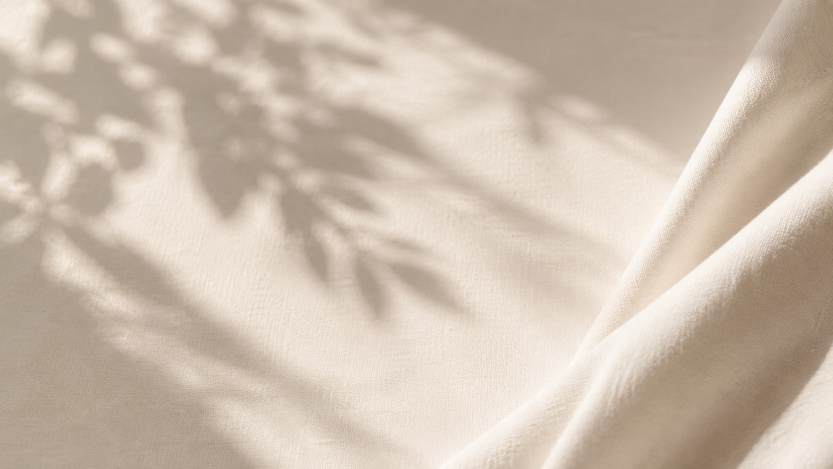 Soft ivory fabric with natural leaf shadows.